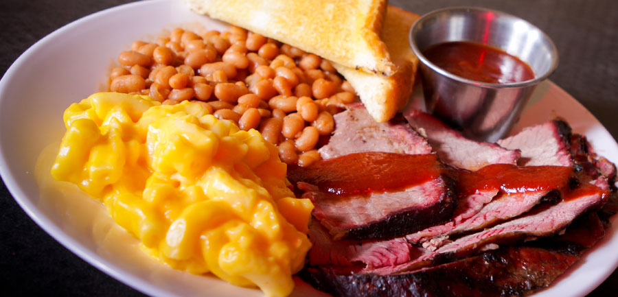 A Bar-B-Q plate with beans, macaroni and cheese, toast, and sliced meat